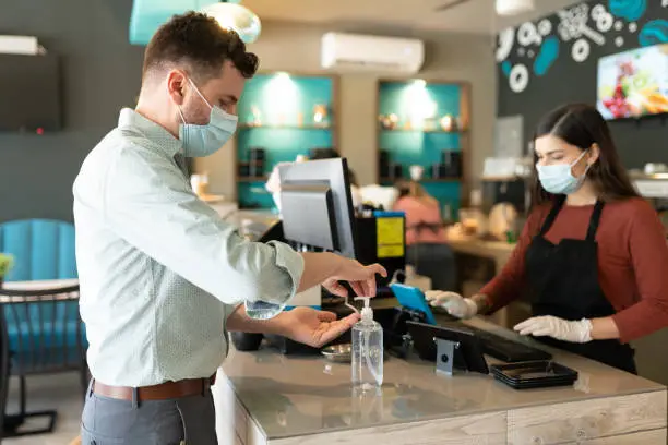 Photo of Man Applying Sanitizer On Hand In Cafe