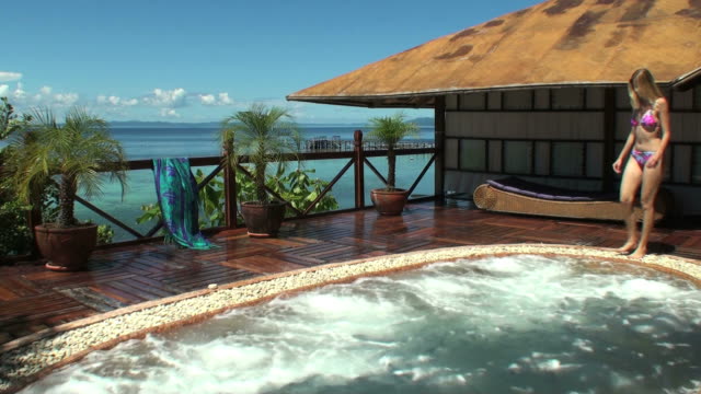 Young woman entering a spa overlooking the ocean and relaxing