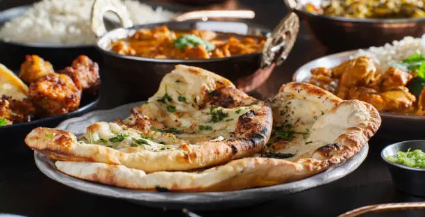 Photo of indian naan bread with herbs and garlic seasoning on plate