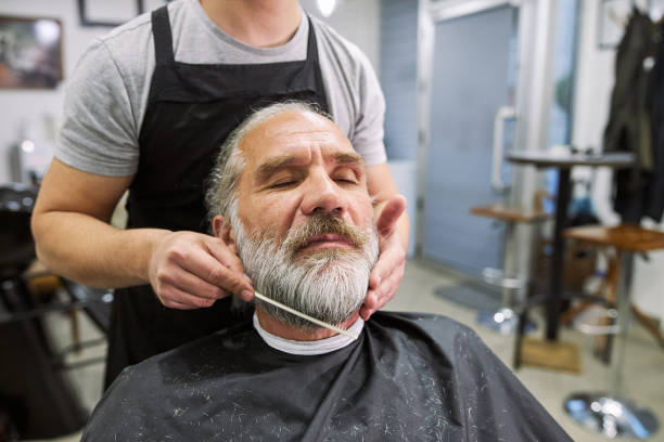 istock Old man getting a beard cut in a barber shop 1253944168