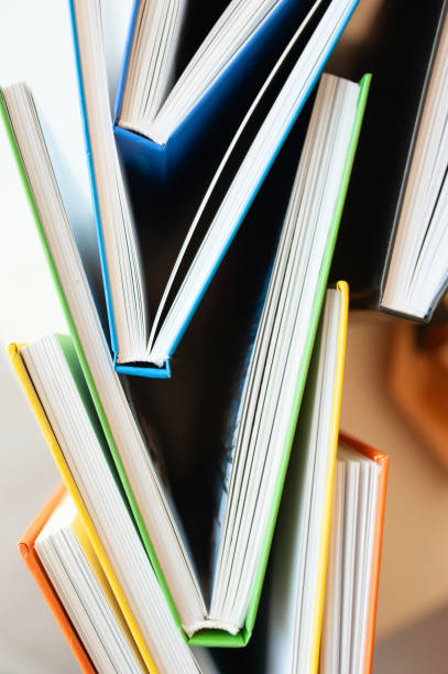 istock vertical image several identical hardcover books with multicolored covers are stacked in each other, top view, selective focus 1253952237
