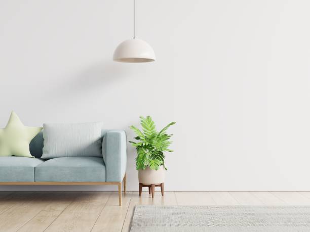 istock Empty living room with blue sofa, plants and table on empty white wall background. 1253952822