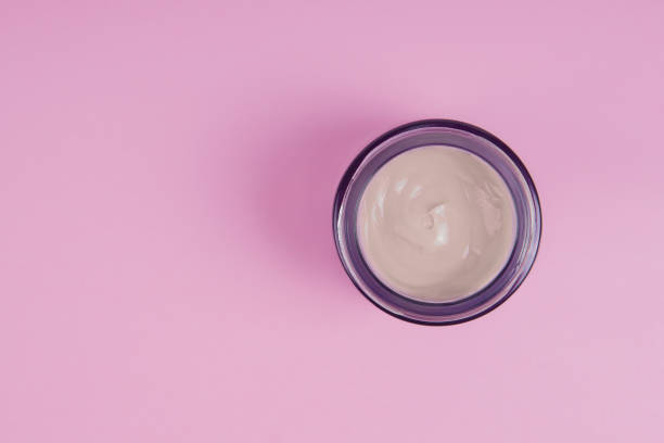 istock Open jar with face cream on a pink background. Face care concept 1253952933