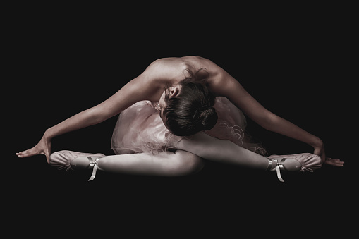 Latin american ballerina posing at studio over black background