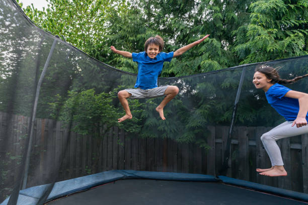 istock Children jumping on a trampoline in a backyard without parents around 1253955400
