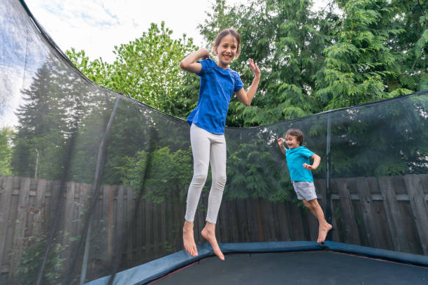 istock Children jumping on a trampoline in a backyard without parents around 1253955401
