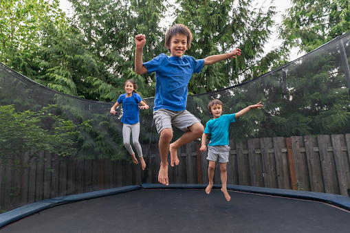 Pretty girl kid jumping on colorful trampoline at playground park and smiling. Caucasian preteen child during active entertaiments indoor