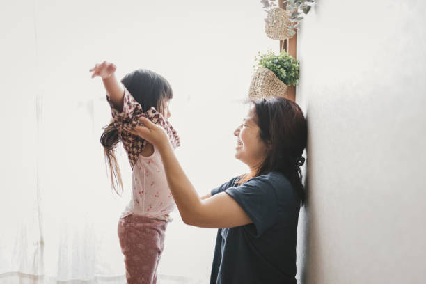 istock Mother help her daughter change clothes 1253961141