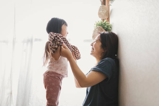 istock Mother help her daughter change clothes 1253961166