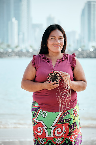 Portrait Of Indigenous Woman Showing Off Woven Coaster And Souvenirs For Sale At Touristic Market Stall, Ciudad De Panama, Panama.