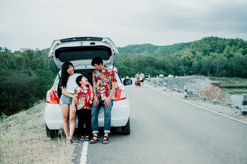 Happy family enjoying road trip and summer vacation with mountain background.