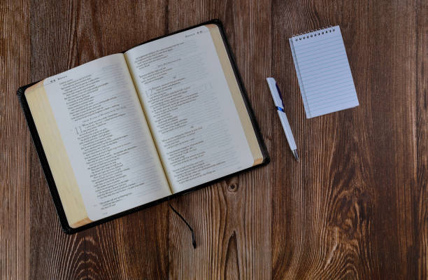 istock Religious christian opened Bible on wooden table with pen spiral notepad 1253967527