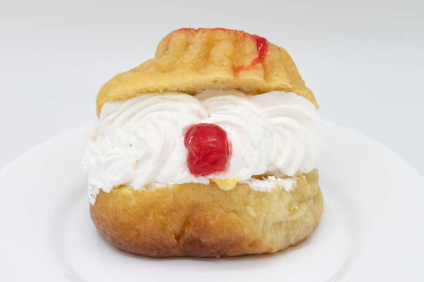 istock Rum Baba with Cream and a Cherry on a White Plate with a White Background 1253967555