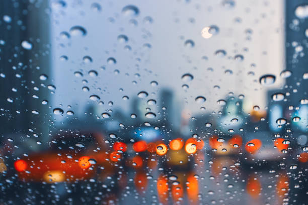 driving car on metropolis road in trafic jam with raindrop over the wind shield, rainy season