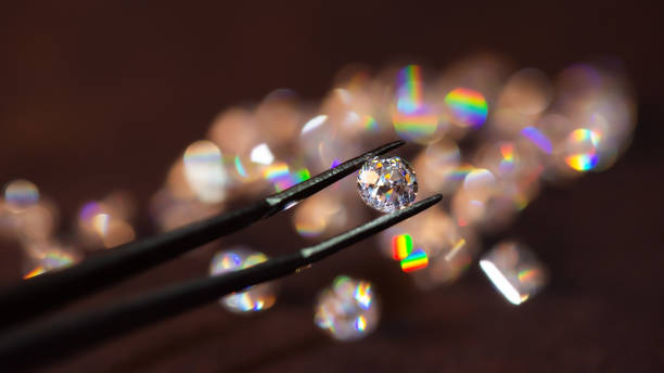 istock Diamond in tweezers on a dark background with diamonds group soft focusing 1253968443