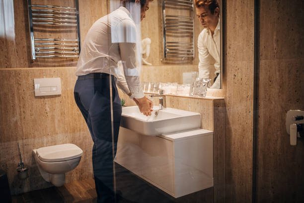Modern man washing hands in hotel room bathroom One man, handsome man washing hands in hotel room bathroom. guest bathroom stock pictures, royalty-free photos & images