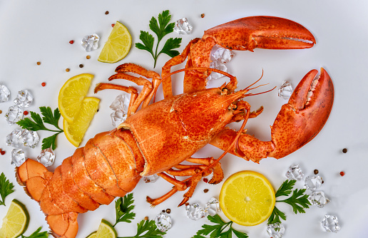 Boiled crab with lemon, parsley and black pepper on white background. Top view.