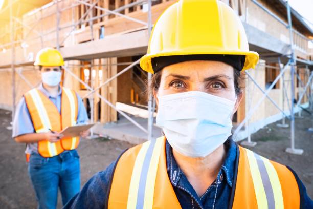 istock Mature female construction worker looking at the camera wearing a protective face mask 1253978191
