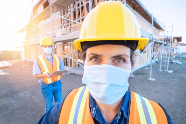istock Mature female construction worker looking at the camera wearing a protective face mask 1253980309