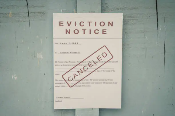 Photo of Canceled Foreclosed or eviciton notice on a main door with blurred details of a house with vintage filter.