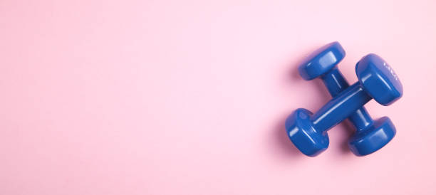 istock Blue dumbbells on pink background. 1253982167