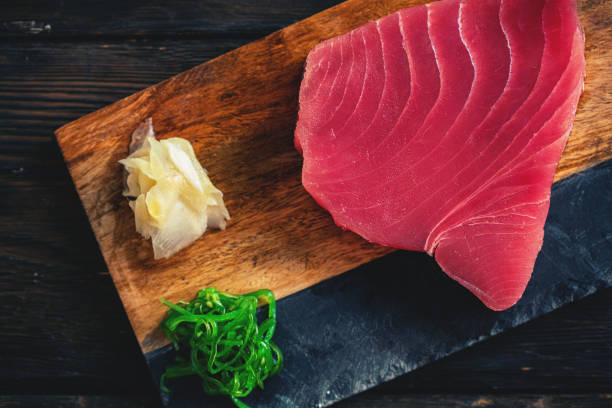 rohes thunfischsteak mit zutaten auf einem schneidebrett - vitamin d salmon fillet raw stock-fotos und bilder
