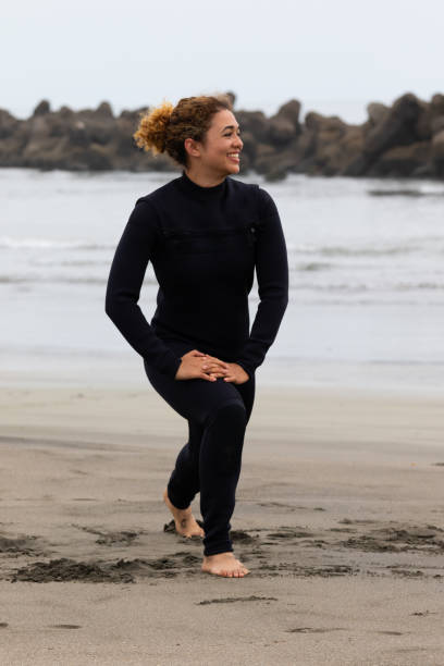 istock Young multiracial African American lady doing pre surfing exercise on a beach 1253987867