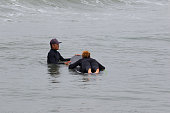 サーフィンを学ぶ若い多民族アフリカ系アメリカ人女性。日本人男性インストラクターと一緒に。彼女は千葉日本でサーフィンをしています