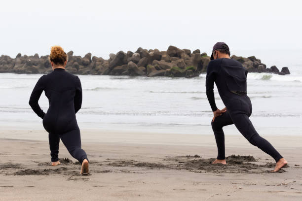 istock Young multiracial African American lady & an Asian man Surf Instructor doing pre surfing exercise 1253987942