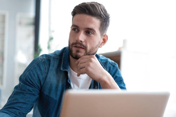 istock Handsome modern man designer working on laptop online, using internet at home 1253992478