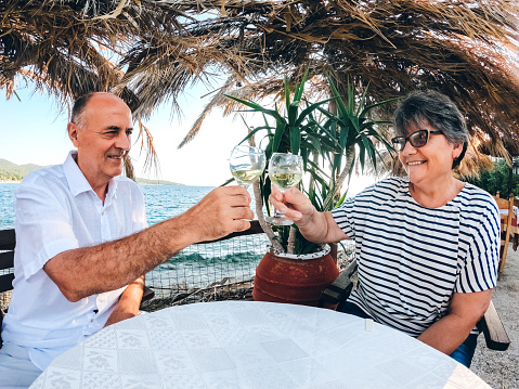 Senior caucasian couple drinking wine in a restaurant by the sea.