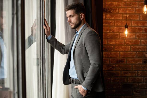 istock Thinking businessman in the office looking through the window. 1253994328