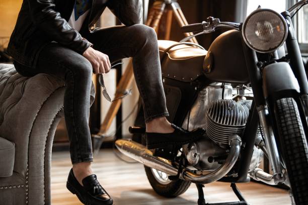 istock Handsome young man in leather jacket looking away while sitting on the stool 1253994451