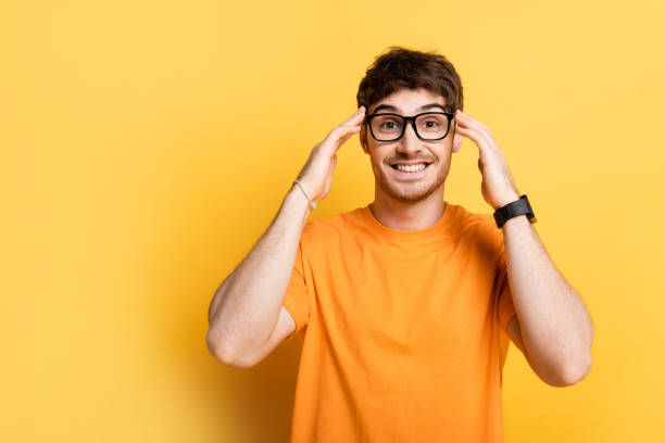 istock happy young man touching head while looking at camera on yellow 1253998284