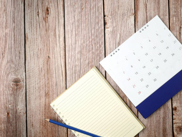 istock Calendar with a notebook on wood texture background 1253999269