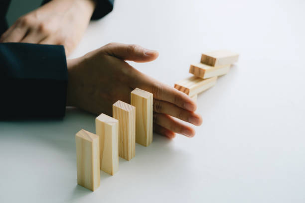 istock businessman hand stopping the domino effect. executive and risk control concept 1254001865