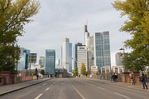 Frankfurt, Hesse / Germany - Nov 23, 2019: Skyline of Frankfurt. Street view from Untermainbrücke towards the financial district / city center with skyscrapers. Framed by trees, panorama format