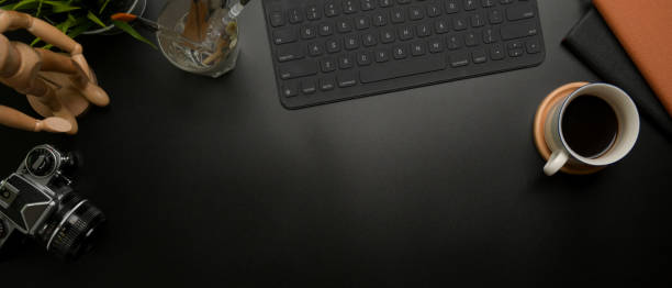 istock Copy space on dark luxury office desk with wireless keyboard, supplies, coffee cup and decorations 1254009639