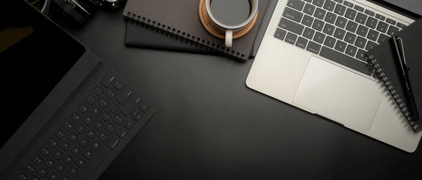 istock Dark modern workspace with digital tablet, laptop, coffee cup, schedule books and copy space 1254009669