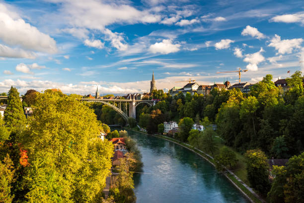 Stunning panoramic view of riversides of Aare river in Bern city, Switzerland Stunning panoramic view of riversides of Aare river in Bern city, Switzerland. Arch bridge, rooftops and tower of Munster cathedral. Snowcaped alpine peaks on background. Picturesque sky bern photos stock pictures, royalty-free photos & images