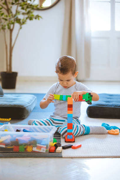 istock Little boy sitting on floor and playing with toy blocks 1254010891