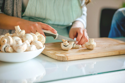 Chopping mushrooms on the cutting board with kitchen knife