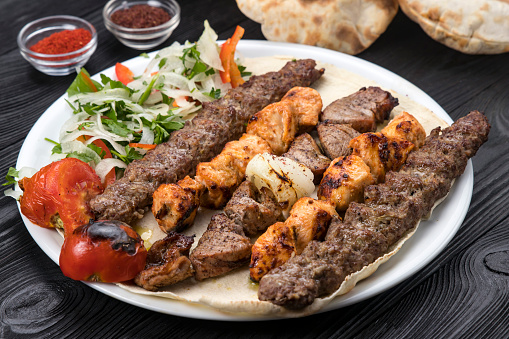 grilled meat on pita bread with salad on a black wooden background