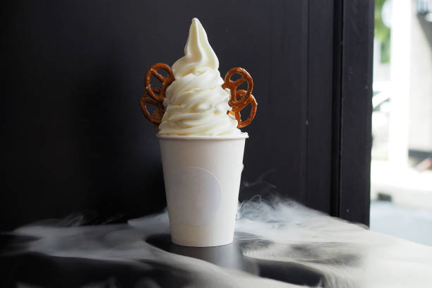 Frozen yogurt ice cream in a disposable cup; takeaway decorated with cornflake and pretzel served with dried ice making amazing moment.