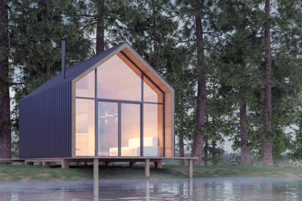 Secluded tiny house on the sandy shore of a lake with fog in a coniferous forest in cold cloudy lighting with warm light from the Windows. Stock 3D illustration Secluded tiny house on the sandy shore of a lake with fog in a coniferous forest in cold cloudy lighting with warm light from the Windows. Stock 3D illustration tiny house stock pictures, royalty-free photos & images