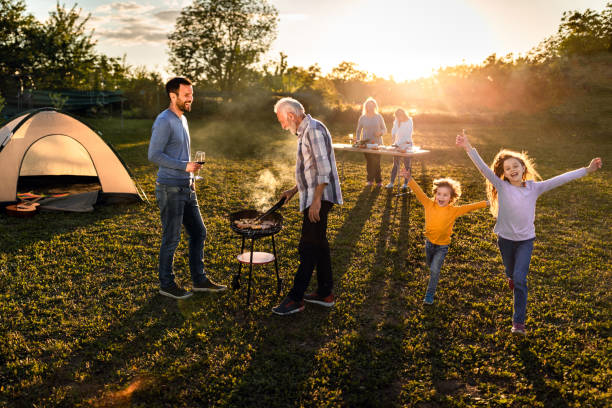 famille étendue heureuse ayant une partie de jardin de barbecue au coucher du soleil. - tent camping lifestyles break photos et images de collection