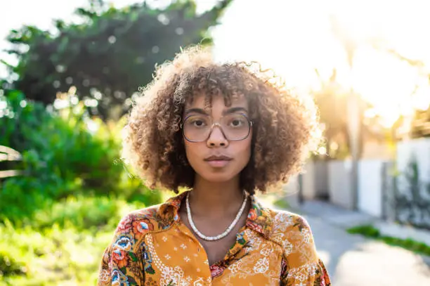 a young black woman with glasses, at sunrise next to the city the nature