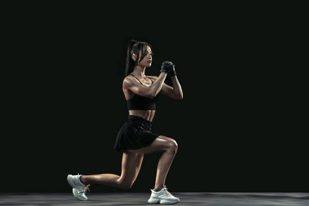 istock Beautiful young female athlete practicing on black studio background, full length portrait 1254022173