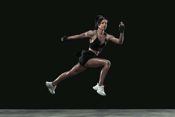 istock Beautiful young female athlete practicing on black studio background, full length portrait 1254022175