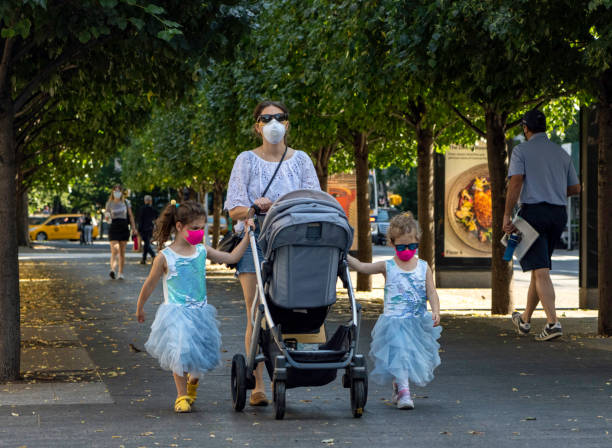 mother, young girls in princess dresses, hot pink masks out walk on fifth avenue during coronavirus - group of people art museum clothing lifestyles imagens e fotografias de stock